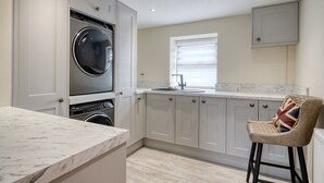 A modern kitchen with built-in appliances, a marble countertop, and a bar stool. - The Oak, Country Home, Sleeps 4 with Hot Tub (Oakenshaw)