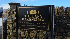 A sign for The Barn Oakenshaw, a luxury holiday accommodation, with a stone wall and snow-covered ground. - The Oak, Country Home, Sleeps 4 with Hot Tub (Oakenshaw)