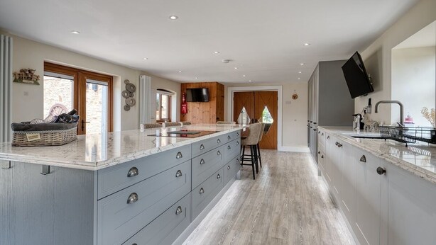 A spacious kitchen with a large island, wooden cabinets, and a built-in TV. - The Oak, Country Home, Sleeps 4 with Hot Tub (Oakenshaw)