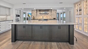 A modern kitchen with a central island, built-in appliances, and a stone accent wall. - Ocean Commotion by Distinctive Beach Rentals (Ponte Vedra Beach)