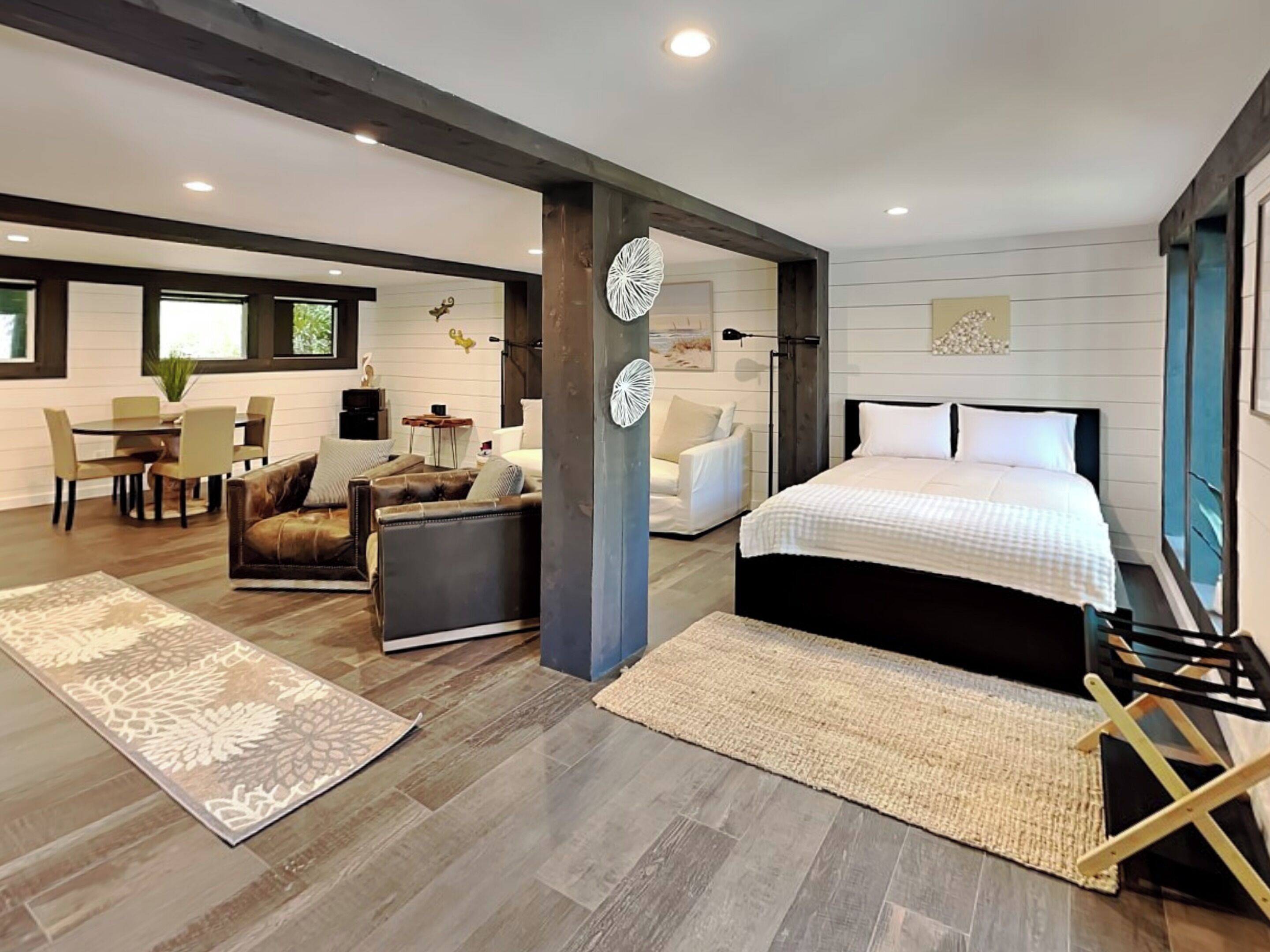 A modern bedroom with a large bed, a sitting area with a sofa and chairs, and a dining area with a table and chairs.