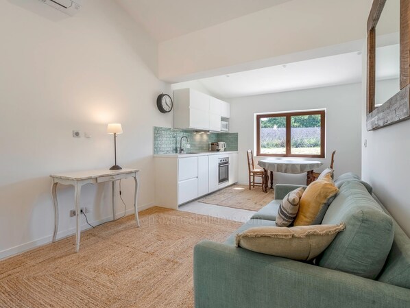 Un espace de vie compact comprenant un coin cuisine, un coin repas et un espace détente avec un canapé et une table.