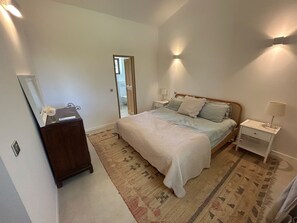 A bedroom with a bed, bedside tables, a dresser, and a mirror.