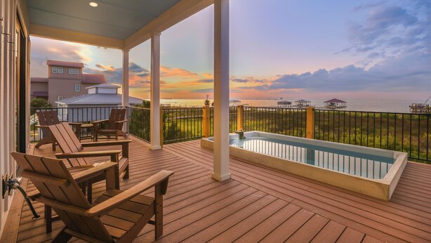 A wooden deck with a pool, chairs, and a view of the ocean at sunset. - New! 5BD+Private Pool! 3 Decks with amazing views! (Gulf Shores)