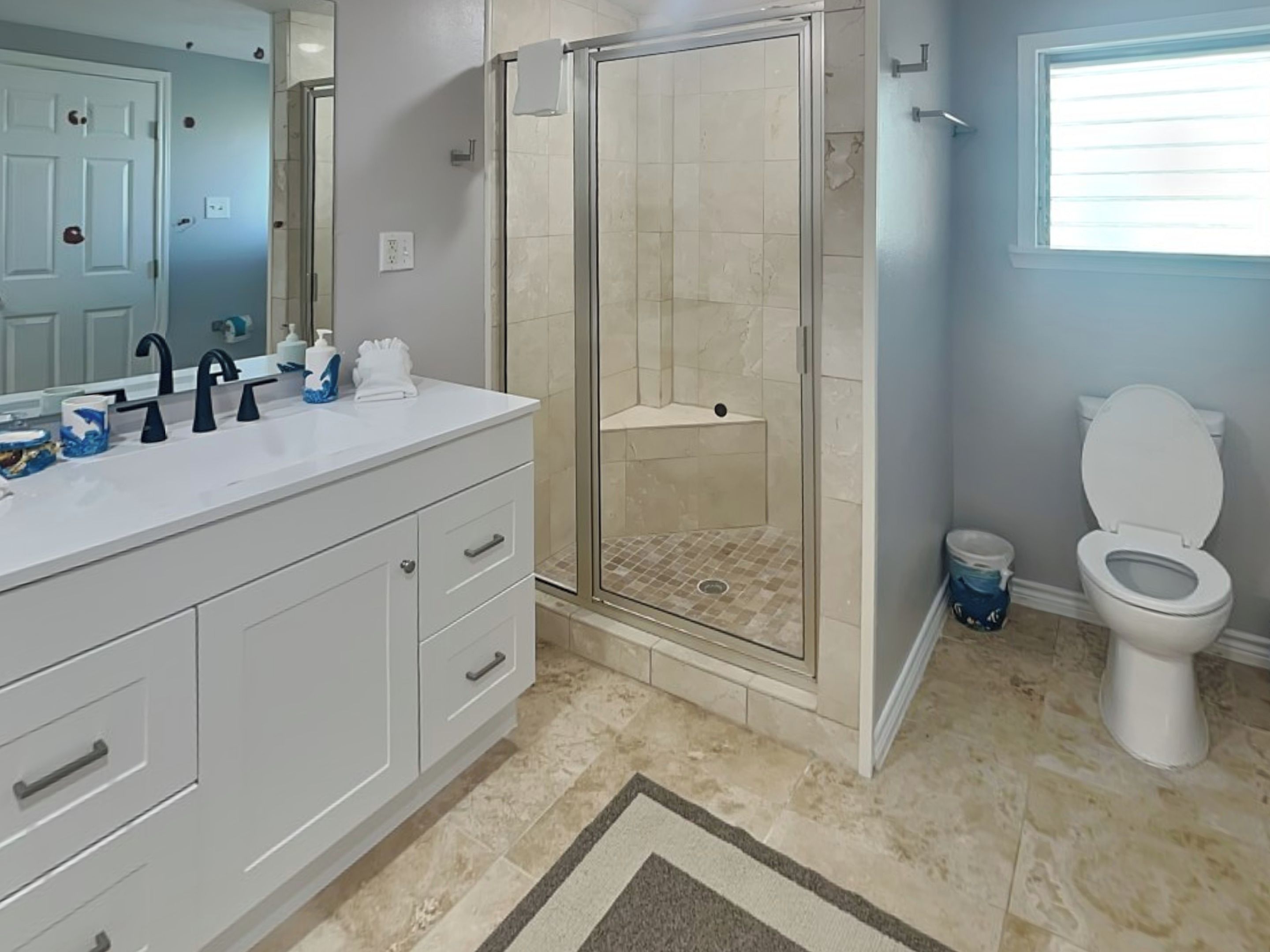 A modern bathroom with a walk-in shower, a white sink with a mirror, and a toilet.