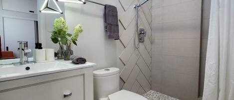 Un baño moderno con un tocador blanco, ducha con puerta de cristal y un inodoro.