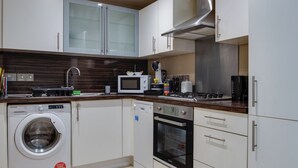 Una cocina moderna con armarios blancos, microondas integrado, lavavajillas y estufa.