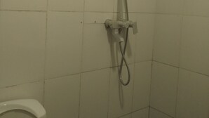 A shower area with a handheld showerhead and a wall-mounted faucet. - Your Cozy 1-bedroom, for short or long stays; minutes from the ocean and dining! (Dar es Salaam)