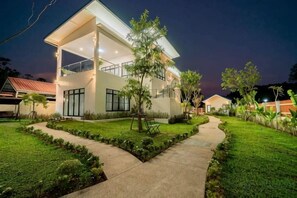 A modern two-story house with a covered patio, a well-maintained lawn, and a pathway leading to the entrance. - Villa Alawan (Krabi)