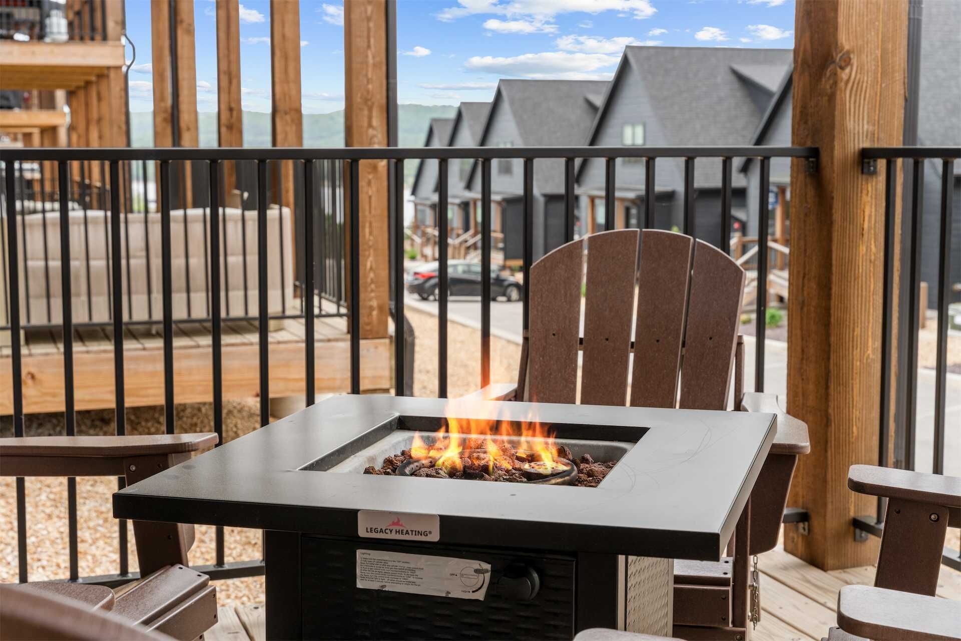 Eine Terrasse mit einem Metalltisch und -stühlen, einer Feuerstelle und Blick auf eine Wohngegend.