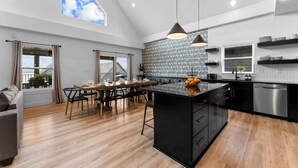 Una cocina moderna con una isla central, armarios negros e iluminación colgante.