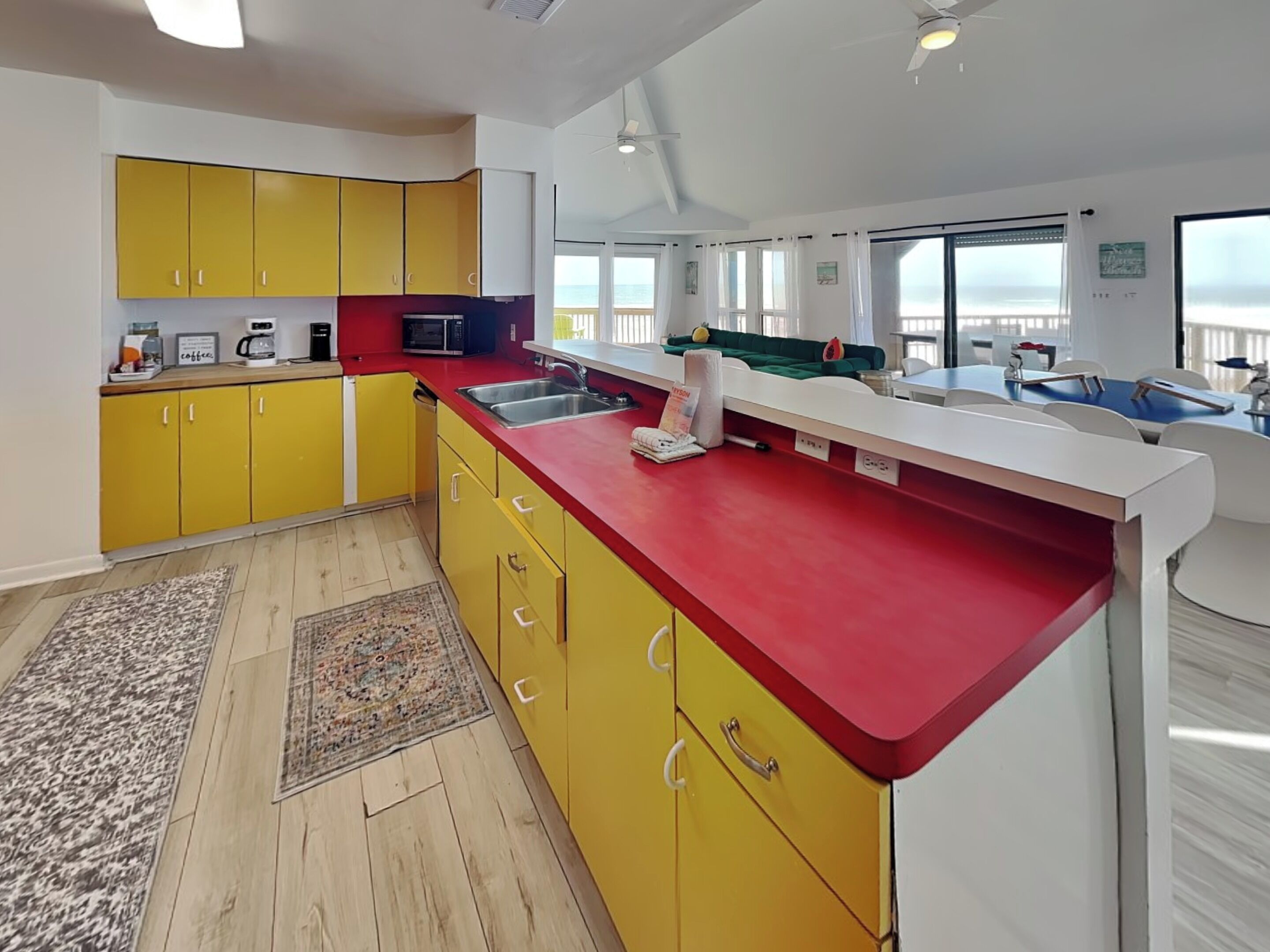 Una cocina moderna con armarios amarillos, encimera roja y vistas al océano.