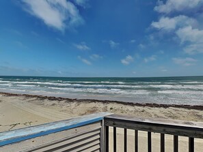 A beach view with waves, a wooden deck, and a clear sky. - Pirates Beach Retreat by Ryson Vacation Rentals (Galveston)