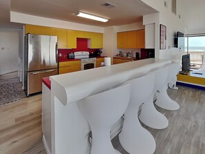Une cuisine moderne dotée d’un îlot central, d’appareils électroménagers en acier inoxydable et de meubles de couleur jaune.