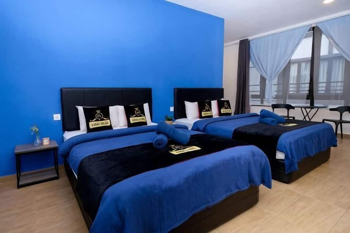 Een hotelkamer met twee bedden, een tafeltje en een raam met gordijnen.