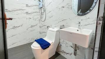 A bathroom with a toilet, a sink, and a mirror.