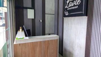 A reception desk with a wooden counter, a black sign above it, and vertical paneling on the walls.