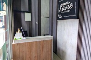 Ein Empfangsschalter mit einer Holztischplatte, eine schwarze Beschilderung darüber und vertikale Wandverkleidungen.