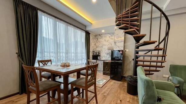 Uma sala de jantar com mesa e cadeiras, uma escada em espiral e um sofá verde.