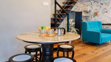 A dining area with a round table, four chairs, and a blue sofa.