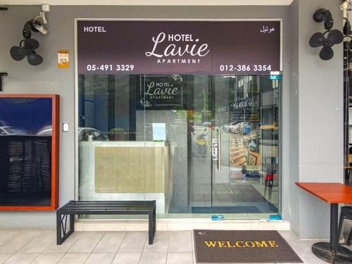 A hotel entrance with a reception desk, a welcome mat, and a glass door.