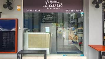 A hotel entrance with a reception desk, a welcome mat, and a glass door.