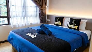 Een hotelkamer met een groot bed, een raam met gordijnen en een bord op de muur.