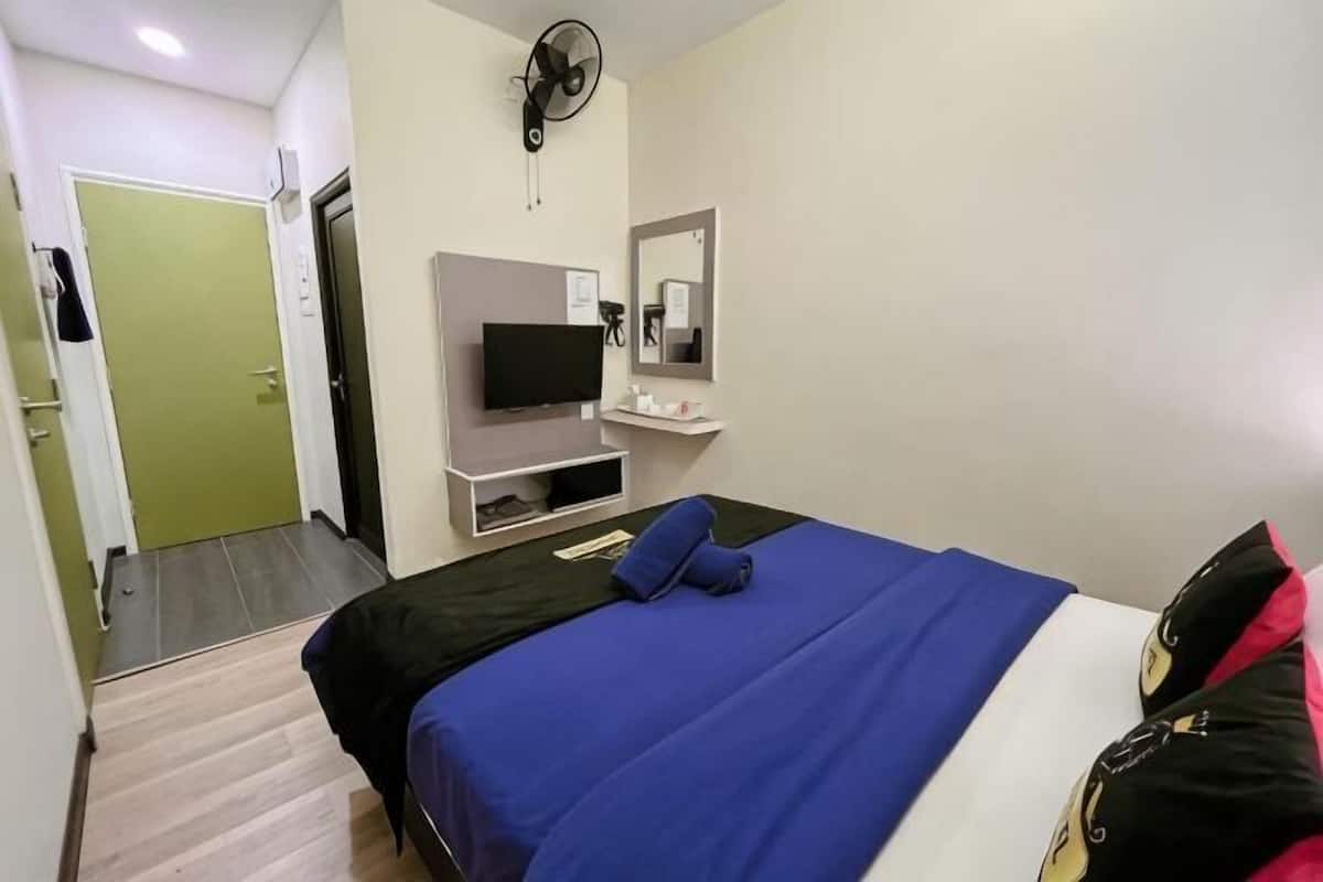 Een hotelkamer met een bed, een televisie, een spiegel en een ventilator.