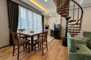 A dining area with a table and chairs, a spiral staircase, a green sofa, and a kitchen area. - Hotel Lavie at Centrum (Brinchang)