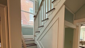 Una scala con pareti bianche e gradini in legno scuro che conduce a un pianerottolo.