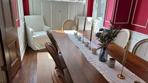 Un'area pranzo con un tavolo in legno, sedie bianche e un vaso con fiori.