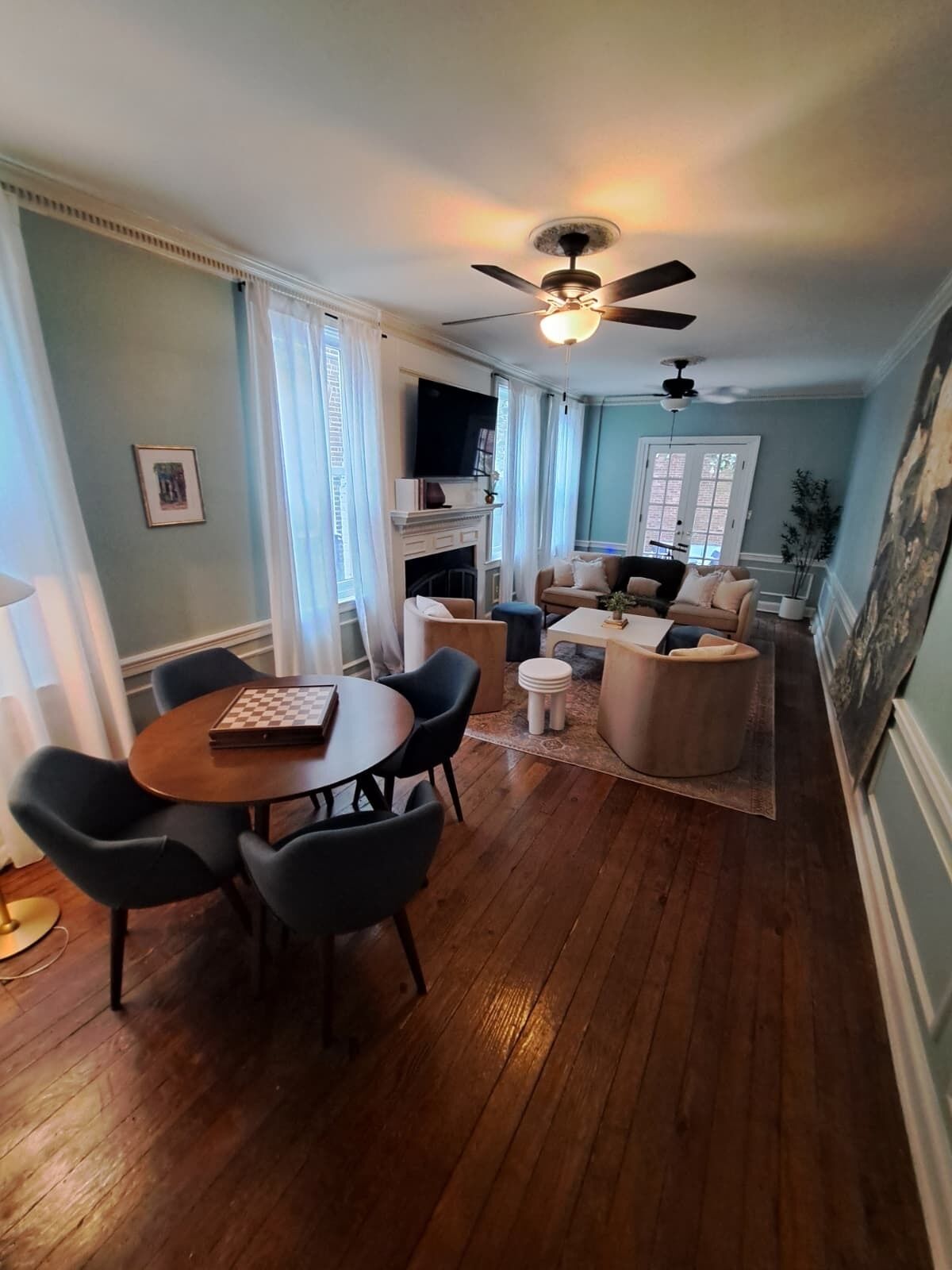 Un salon spacieux avec une cheminée, un coin repas avec une table et des chaises, et un ventilateur de plafond.