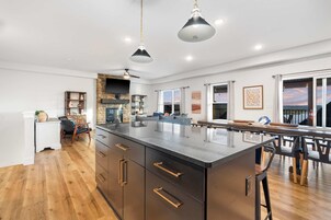 Una cocina amplia con una isla central, piso de madera e iluminación colgante.