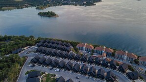 Ett bostadsområde med en stor sjö, en liten ö och en rad hus, där en parkeringsplats syns tydligt i förgrunden.
