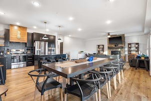 A modern kitchen with a central island, stainless steel appliances, and a dining area with bar stools.