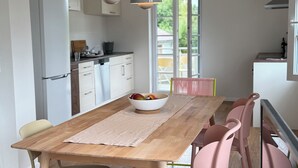 Una cocina moderna con armarios blancos, una mesa de madera y sillas rosadas.