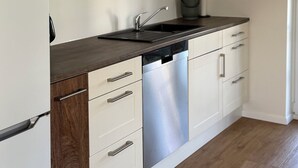 Una cocina moderna con armarios blancos, lavavajillas de acero inoxidable y encimera de madera.