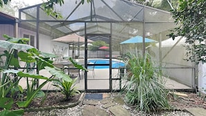 A greenhouse with a pool, surrounded by plants and a stone pathway. - Rivers Edge Retreat by Distinctive Beach Rentals (St. Augustine)