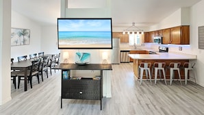 A modern kitchen with wooden cabinets, a central island with bar stools, and a dining area with a table and chairs. - Rivers Edge Retreat by Distinctive Beach Rentals (St. Augustine)