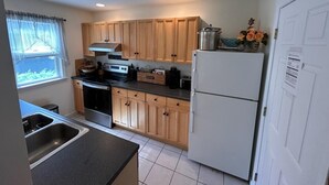 Una cocina con armarios de madera, un refrigerador, una estufa y un fregadero.