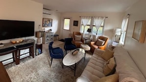 Una sala de estar con televisor de pantalla plana, una mesa de centro, sofás y sillones.