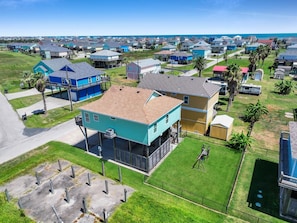 A residential area with houses, a parking lot, and a clear view of the ocean. - Anchors Away-Sleeps 10, Fully Fenced Back Yard, Play Set, Walk to Beach, Pets OK (Bolivar Peninsula)