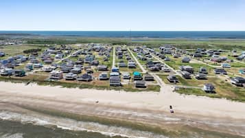 An aerial view of a coastal residential area with houses and a beach.