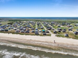 An aerial view of a coastal residential area with houses and a beach. - Ibis Isle-Bolivar Peninsula, Sleeps 12, Fenced Side Yard, Walk to Beach, In Town (Bolivar Peninsula)