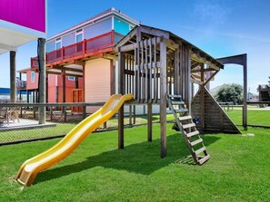 A playground with a slide and a climbing structure. - Ibis Isle-Bolivar Peninsula, Sleeps 12, Fenced Side Yard, Walk to Beach, In Town (Bolivar Peninsula)