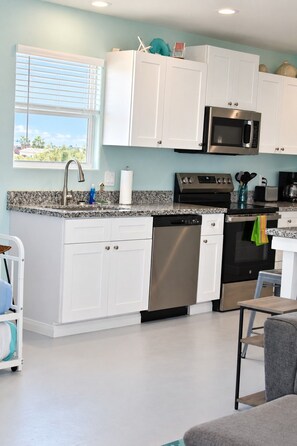 A modern kitchen with white cabinets, a stainless steel dishwasher, a black oven, and a microwave.