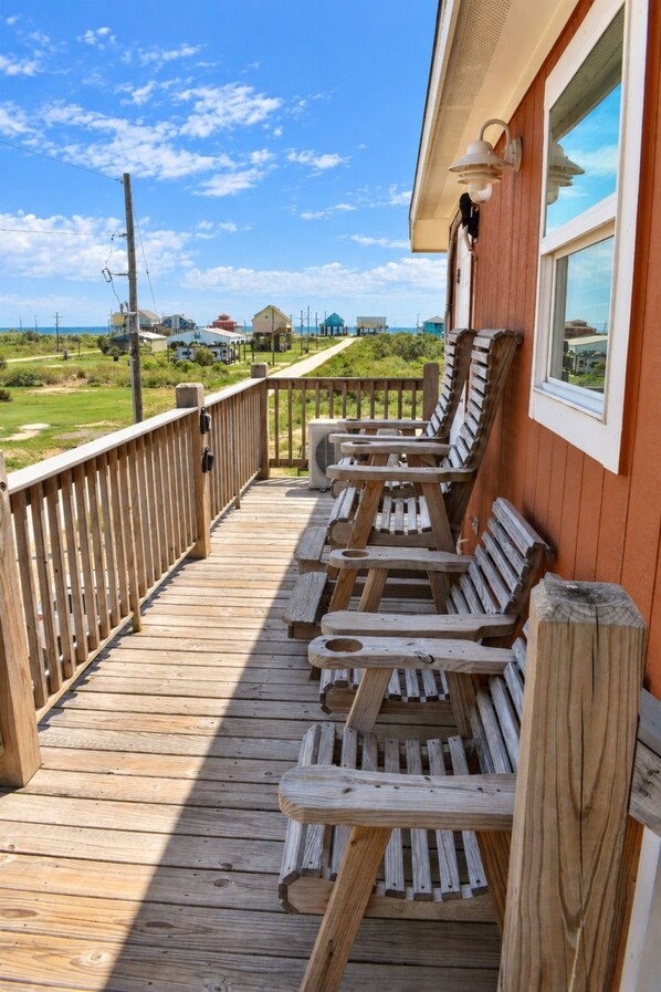 Une terrasse en bois avec des sièges extérieurs et vue sur la plage.