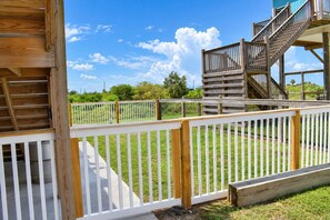 Eine Holzterrasse mit weißer Brüstung, einer Treppe und einem Rasenbereich.