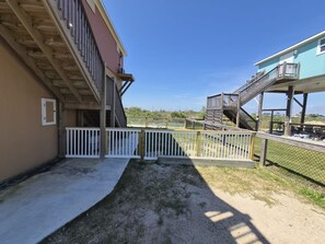 Un bâtiment doté d’une terrasse en bois, d’une clôture blanche et surplombant un ciel dégagé.