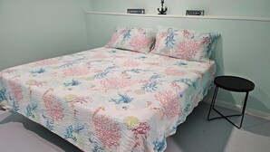 A bed with a floral quilt, a small black stool, and two signs on the wall reading "Serenity" and "Ocean". - Crabby Cove - Fully Fenced Side Yard, Pets OK, Gulf & Bay Views, Walk to Beach (Bolivar Peninsula)